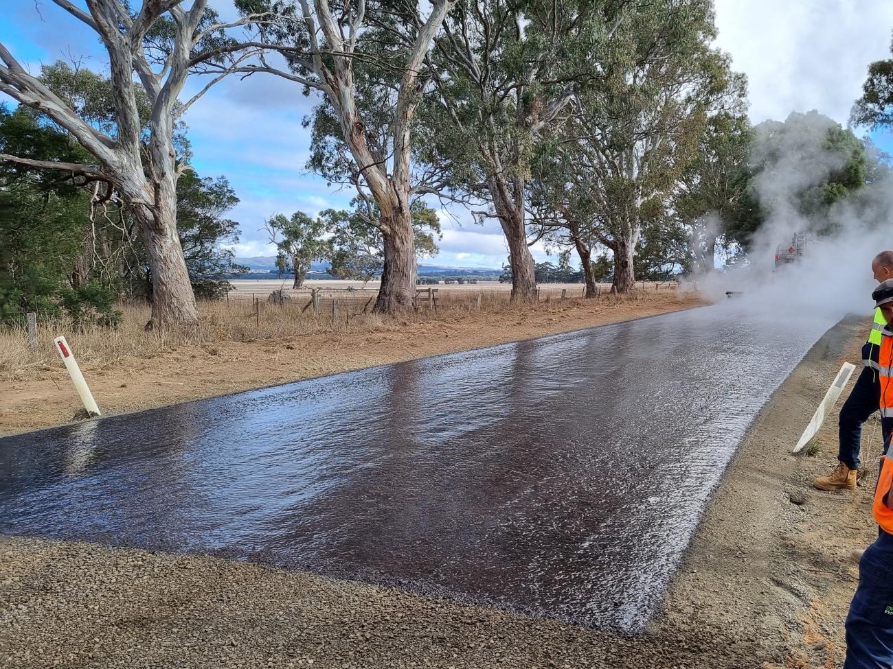 A road crew applies a fresh spray seal of bitumen to a rural road in Ararat, Victoria.