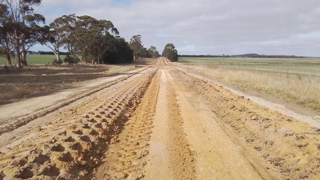 A long rural road whose soil has been prepped for a new surface