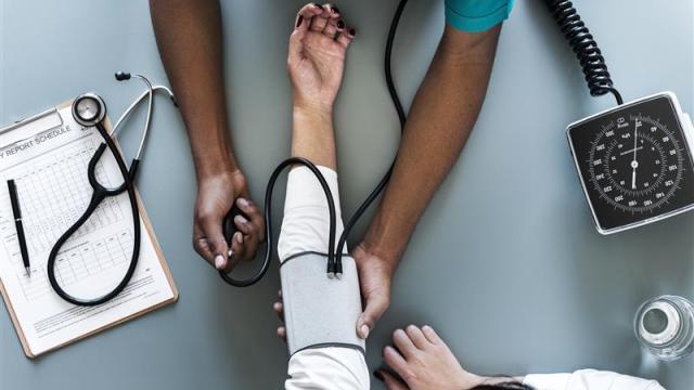 Birds-eye view of a doctor taking a woman's blood pressure