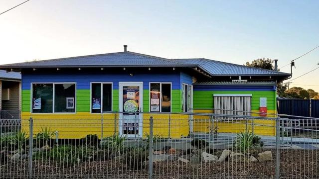 A house painted in bright yellow, blue and green horizontal stripes