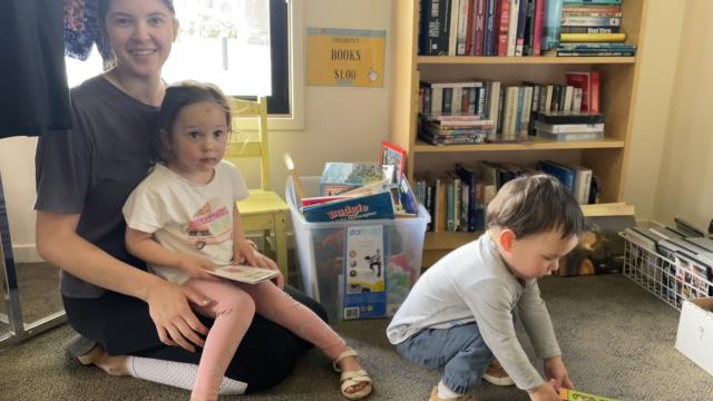 A young woman reading a book to a child, both smiling