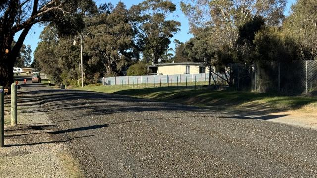 Freshly-sealed rural road with sunshine in sky