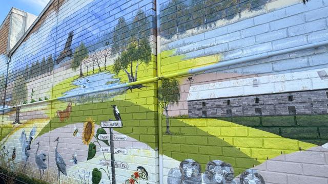 A mural of wildlife and landscape, painted on a large brick wall