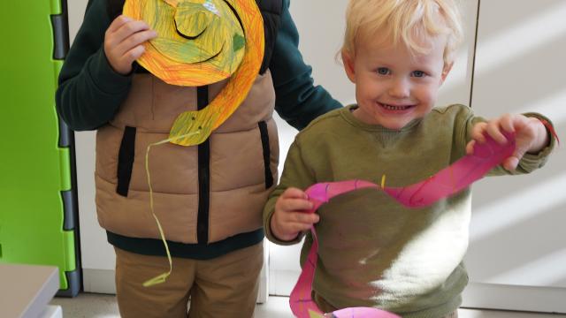 Two children smiling and holding up their artworks
