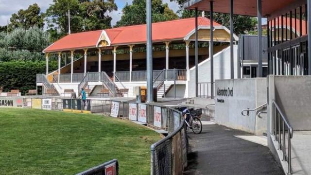 The edge of a suburban football oval with bleacher stands and a pavilion