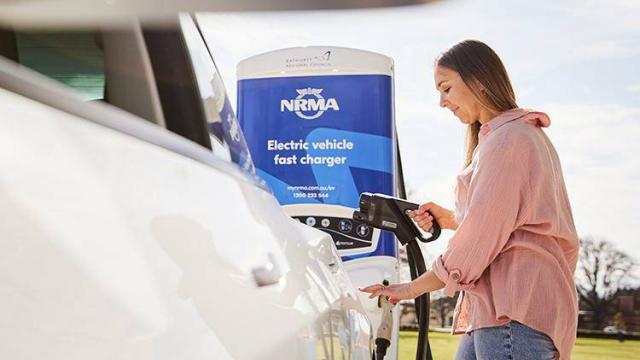 Woman charging her electric vehicle with a far car charger