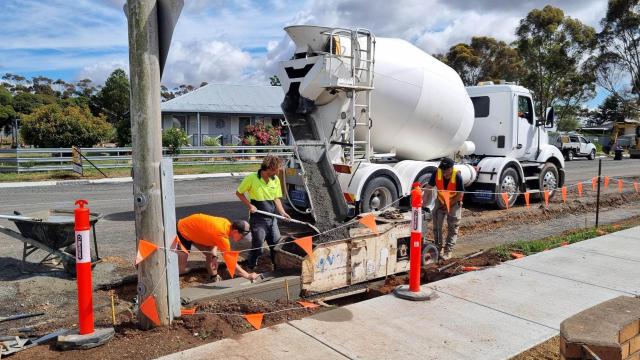 Fresh concrete poured on a street's kerb and channel with orange construction flags
