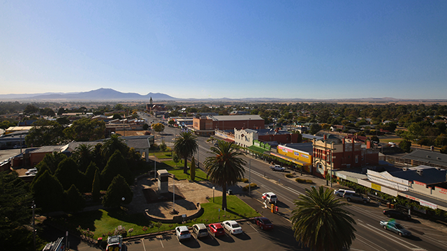 Long shot of a rural township on a sunny day with mountains in the background