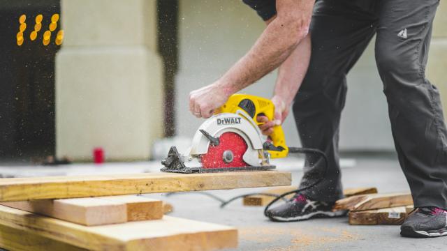 A man in dark work pants is operating a concrete cutter on a building site