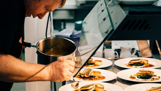Chef in the kitchen putting finishing touches on several plated dishes