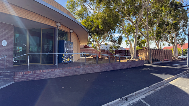 Sun shining on a freshly laid bitumen footpath on an urban street