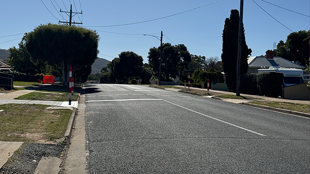A residential street on a sunny day with trees along its nature path