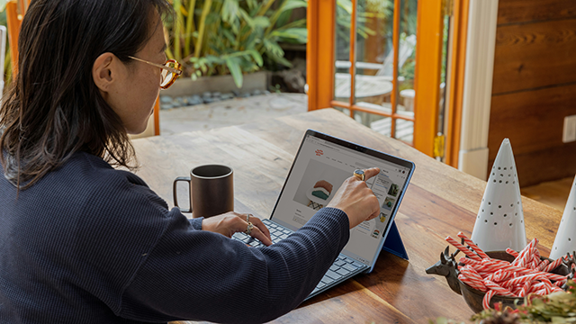 A woman working on a laptop with a mug of coffee sitting beside her on the table