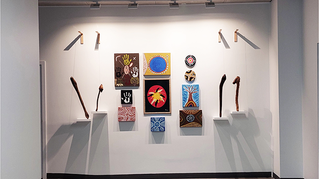 A gallery wall with art hung under spotlights