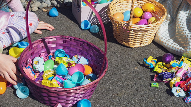Two children sitting on the ground with easter egg baskets and sweets