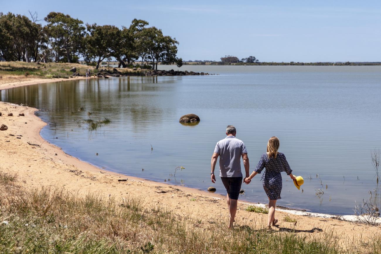 A couple are holding hands and walking to the Green Hill Lake